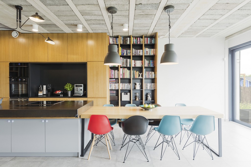 Interior in an industrial style with an open kitchen, dining table and colorful chairs - Shutterstock : 441051442 - Photographee.eu